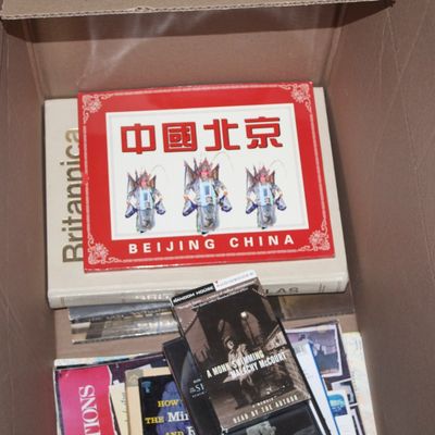 Sale Photo Thumbnail #147: Cardboard box packed with mixed media, including a Beijing China pictorial book, a Britannica atlas, cassette audiobooks, and assorted paper ephemera.