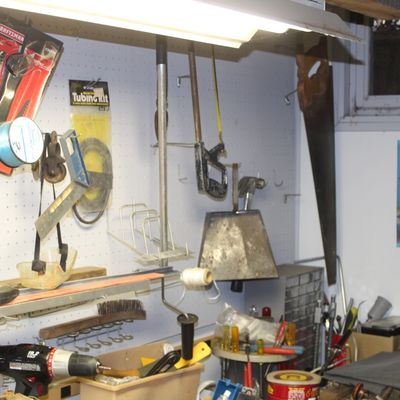 Sale Photo Thumbnail #97: Workshop area featuring pegboard-mounted vintage tools including a brass fire extinguisher, handsaws, packaged Craftsman items, and various hardware accessories.