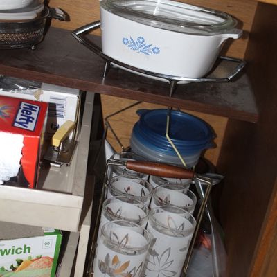 Sale Photo Thumbnail #74: Vintage Corning Ware Blue Cornflower casserole dish with glass lid and metal cradle, stored above a set of mid-century frosted drinking glasses in a metal carrier.
