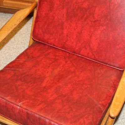 Sale Photo Thumbnail #123: Mid-century modern armchair featuring a sculpted wooden frame and red vinyl cushions.