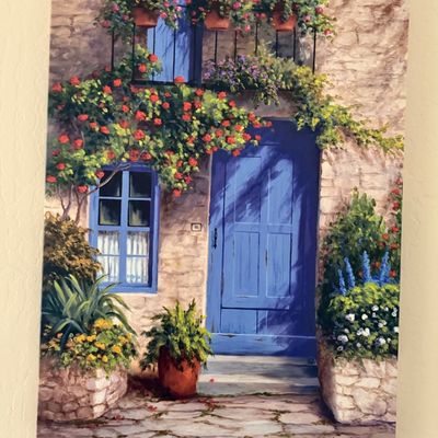 Sale Photo Thumbnail #13: Frameless canvas print depicting a stone house facade with a bright blue door, blue window shutters, and vibrant potted flowers, signed by Barbara R. Felisky.