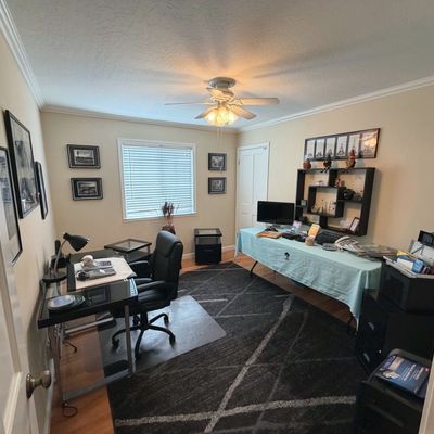 Sale Photo Thumbnail #51: Home office setup including a glass-top computer desk with black rolling chair, a large area rug, display shelving, and various office supplies.