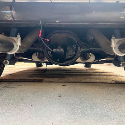 Sale Photo Thumbnail #32: Underside view of a vehicle featuring dual exhaust pipes, rear differential housing, and leaf spring suspension.