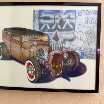 Sale Photo Thumbnail #3: Framed hot rod art print featuring a vintage rat rod set against a skull graffiti background, displayed in a simple black frame.