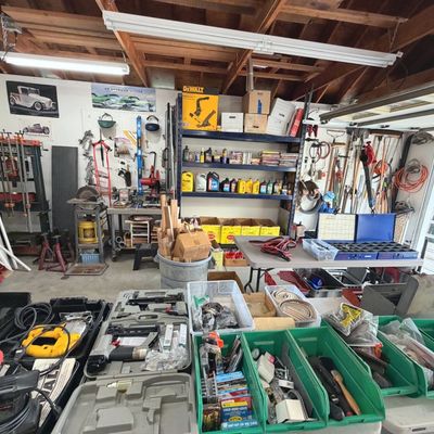 Sale Photo Thumbnail #46: Garage workshop filled with various power tools, hand tools, hardware bins, and shelving units loaded with automotive fluids and supplies.