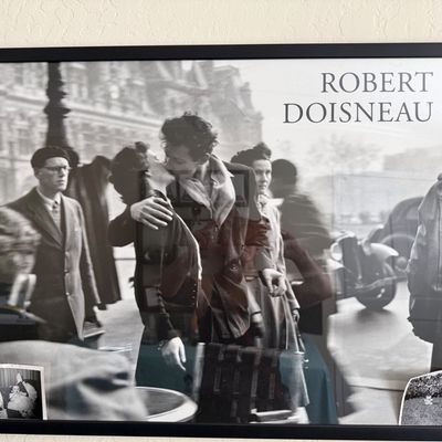 Sale Photo Thumbnail #17: Framed exhibition poster featuring Robert Doisneau's iconic 1950 photograph 'Le Baiser de l'Hôtel de Ville', housed in a simple black frame.