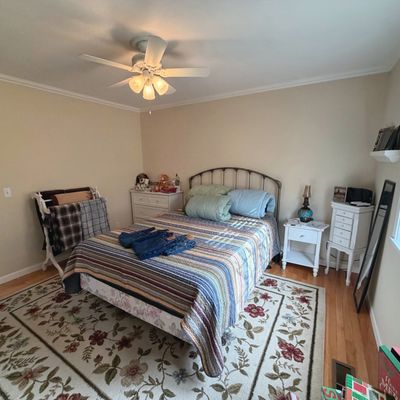 Sale Photo Thumbnail #53: Bedroom set including a metal full/queen bed frame with a striped quilt, white nightstand, tall jewelry armoire, dresser, and a large floral area rug.