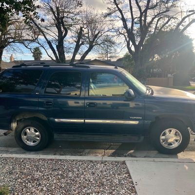 Sale Photo Thumbnail #38: Dark blue GMC Yukon SUV parked on a residential street side.