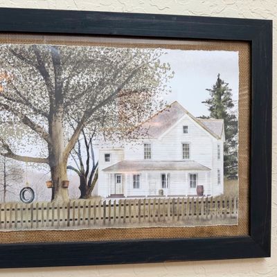 Sale Photo Thumbnail #10: Framed artwork depicting a white farmhouse with a tire swing, mounted on a burlap backing in a dark wooden frame.