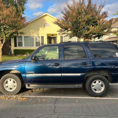 Sale Photo Thumbnail #35: Blue GMC Yukon SUV parked on a residential street in front of a yellow house.