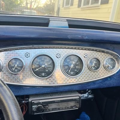 Sale Photo Thumbnail #26: Vintage vehicle dashboard with an engine-turned aluminum instrument panel featuring Stewart Warner gauges and an aftermarket Kenwood stereo below.