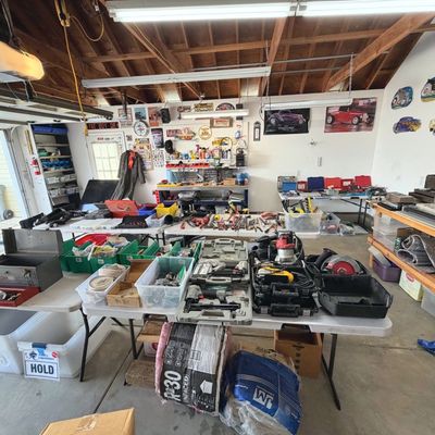 Sale Photo Thumbnail #45: Garage workshop setup featuring folding tables displays of power tools, hand tools, toolboxes, hardware, and automotive wall decor.
