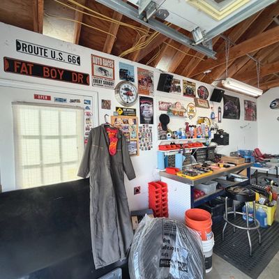 Sale Photo Thumbnail #43: Garage workshop filled with automotive memorabilia, signs, tools, workbenches, and vintage coveralls.