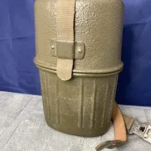 Vintage olive drab military canteen mess kit with textured metal finish and canvas strap assembly.