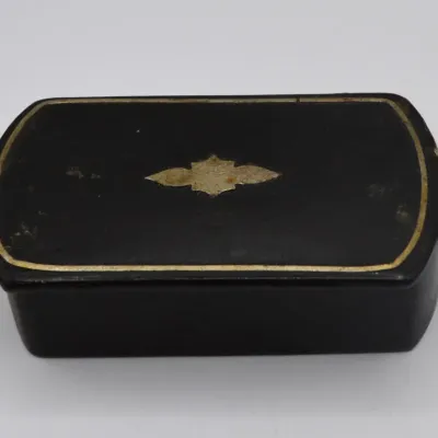 Sale Photo Thumbnail #30: Antique black lacquer trinket box featuring gold-tone trim and a central inlay design on the hinged lid.