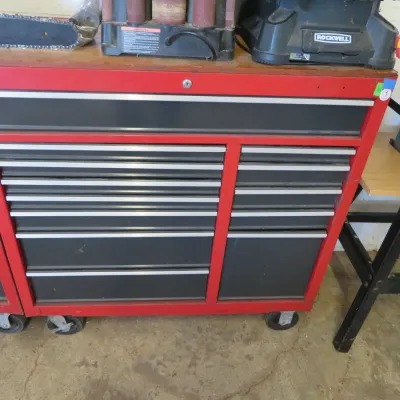 Sale Photo Thumbnail #17: Large red and black rolling tool chest featuring multiple drawers and heavy-duty casters.