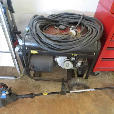 Sale Photo Thumbnail #11: Portable gas-powered generator with coiled heavy-duty extension cord resting on top, displayed alongside a gas string trimmer.