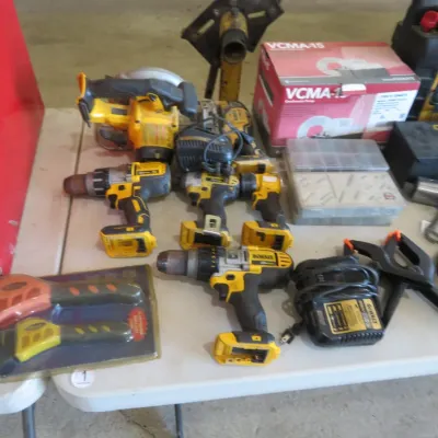 Sale Photo Thumbnail #45: Collection of DeWalt cordless power tools, including drills, impact drivers, a circular saw, chargers, and various hardware accessories on a folding table.
