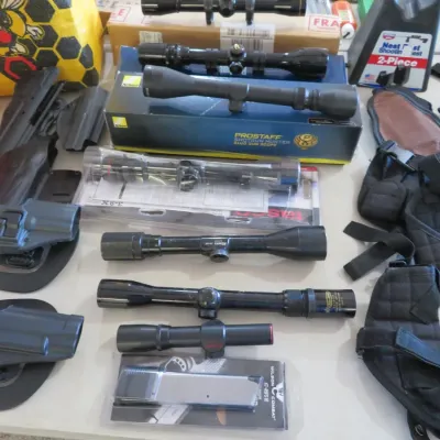 Sale Photo Thumbnail #58: Collection of shooting accessories, including rifle scopes from brands like Nikon and Tasco, assorted gun holsters, tactical harnesses, and a Wilson Combat magazine.