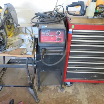 Sale Photo Thumbnail #15: Workshop equipment including a DeWalt miter saw on a folding stand, a Maxus Pro-140 MIG/Flux welder on a rolling cart, and a large red multi-drawer tool chest.