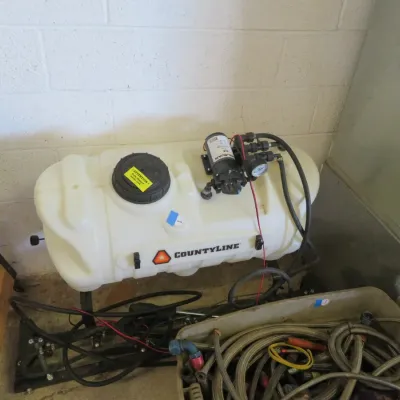 Sale Photo Thumbnail #22: CountyLine spot sprayer featuring a white plastic tank, top-mounted Delavan pump with pressure gauge, and associated hoses stored in a plastic bin below.