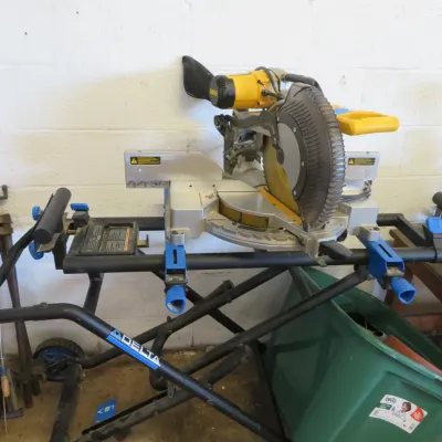 Sale Photo Thumbnail #20: DeWalt compound miter saw mounted on a folding Delta mobile rolling stand, showing signs of light use.