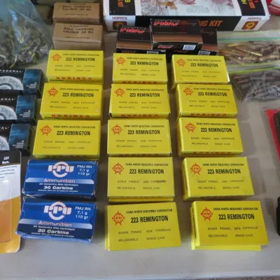 Sale Photo Thumbnail #55: Large collection of ammunition, including yellow boxes of Norinco .223 Remington, PPU .30 Carbine, Federal Power-Shok, and A-Zoom snap caps alongside rifle magazines.