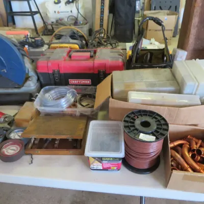 Sale Photo Thumbnail #29: Assortment of workshop tools and hardware, including a chop saw, red Craftsman toolbox, spool of wire, copper pipe fittings, and small storage organizers.