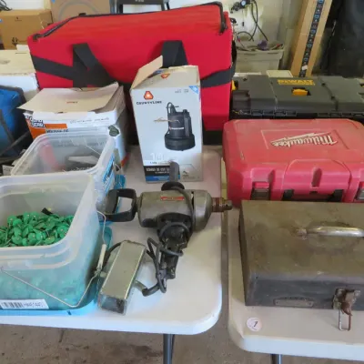 Sale Photo Thumbnail #30: Collection of various power tools and hardware, including a heavy-duty electric drill, Milwaukee hard tool case, vintage metal toolbox, plastic storage tubs filled with fasteners, and a CountyLine utility pump box.