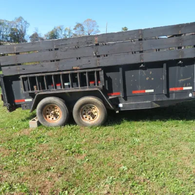 Sale Photo Thumbnail #67: Black Kaufman tandem-axle utility dump trailer with wooden stake side extensions.