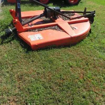 Sale Photo Thumbnail #63: Land Pride orange 3-point hitch rotary cutter attachment resting outdoors on grass, showing light surface wear and debris.