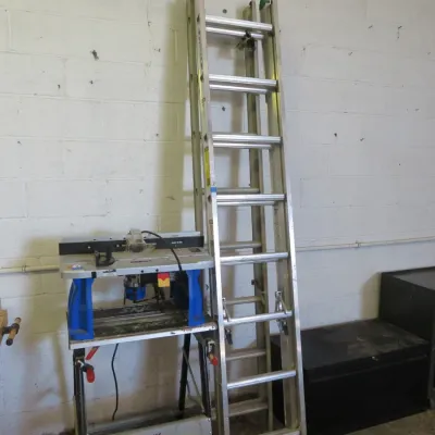 Sale Photo Thumbnail #23: Werner aluminum extension ladder leaning against a wall alongside a benchtop router table.