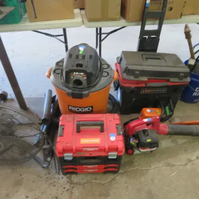 Sale Photo Thumbnail #39: Collection of power tools and equipment, including a Ridgid wet/dry shop vac, red Craftsman toolboxes, a gas leaf blower, and a metal floor fan.