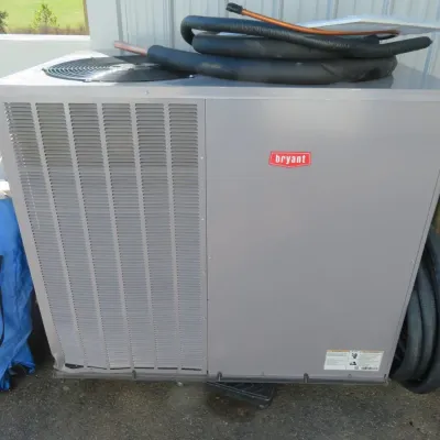Sale Photo Thumbnail #49: Bryant outdoor air conditioning condenser unit with attached insulated copper tubing.