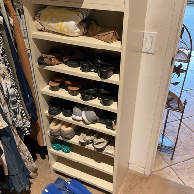 Sale Photo Thumbnail #165: Tall white wooden shoe rack filled with various women's shoes, sandals, slippers, and folded blankets.