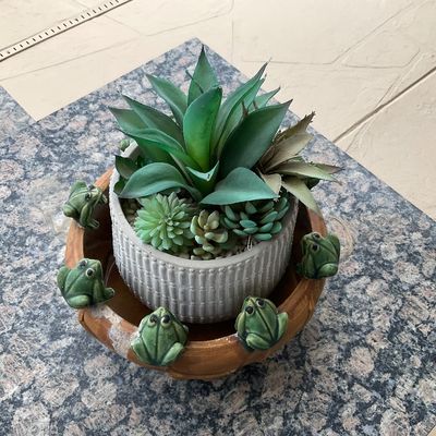Sale Photo Thumbnail #48: Faux succulent arrangement set inside a textured ceramic pot, resting in a vintage brown glazed rim bowl adorned with small ceramic frogs.