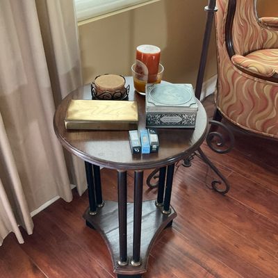 Sale Photo Thumbnail #76: Small round dark wood side table with columnar legs, featuring decorative boxes, coasters, and small accessories on top.