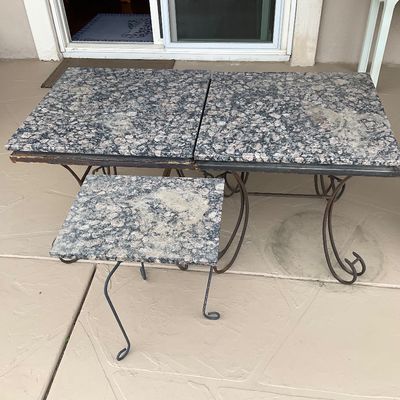 Sale Photo Thumbnail #44: Set of outdoor tables featuring speckled granite tops supported by curved wrought iron bases, showing light weathering and surface wear.