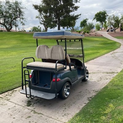 Sale Photo Thumbnail #4: Modern four-passenger electric golf cart featuring a teal body, rear-facing seat, chrome custom wheels, and a canopy roof.