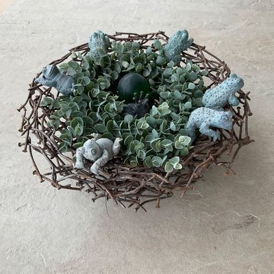 Sale Photo Thumbnail #50: Decorative centerpiece nest fashioned from rusty metal nails, filled with artificial greenery, concrete frog figurines, and a central dark sphere.