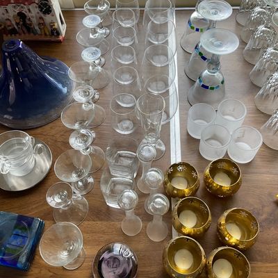 Sale Photo Thumbnail #145: Large assortment of glassware including stemware, tumblers, frosted votive holders, brass tea light holders, and a cobalt blue decorative piece.