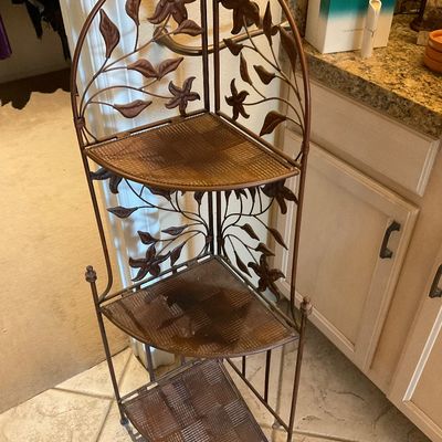 Sale Photo Thumbnail #162: Three-tier bronzed wrought iron corner baker's rack featuring decorative floral and leaf motif details.