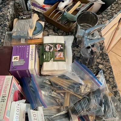 Sale Photo Thumbnail #103: Assortment of modern kitchenware and supplies, including silverware sorted in plastic bags, microfiber cloths, baking utensils, and boxed specialty cake kits.