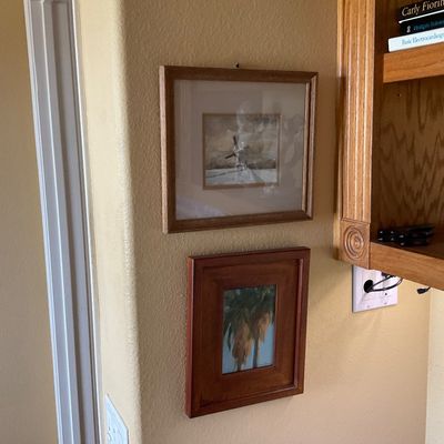 Sale Photo Thumbnail #55: Two small framed artworks, including a matted windmill picture in a light wood frame and a landscape painting in a thick cherry-finish wood frame.