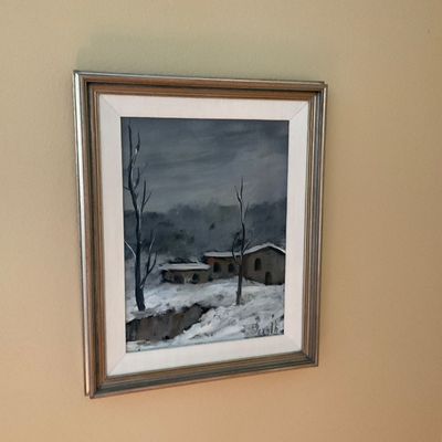 Sale Photo Thumbnail #93: Framed oil painting depicting a winter landscape with snow-covered buildings and bare trees under a stormy sky, signed in the lower right corner.