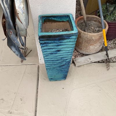 Sale Photo Thumbnail #39: Tall turquoise glazed ceramic planter with horizontal ribbed texture, displayed outdoors alongside other terracotta and ceramic pots.