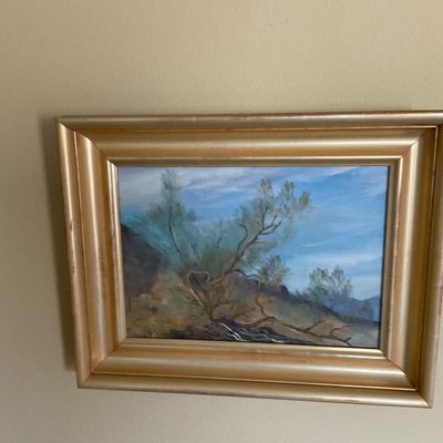 Sale Photo Thumbnail #91: Framed original landscape painting featuring arid desert trees and mountains, set in a wide molded gold-tone frame.