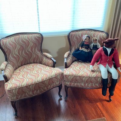 Sale Photo Thumbnail #77: Pair of vintage upholstered barrel-back armchairs featuring wavy pink and beige fabric and dark wood trim, displaying collectible dolls and a fox plush.