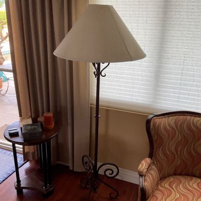 Sale Photo Thumbnail #85: Wrought iron floor lamp with scrolled base details and a large cone lampshade, paired with an upholstered armchair.