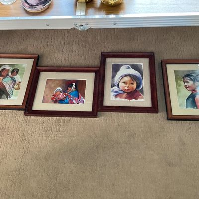 Sale Photo Thumbnail #149: Set of four framed watercolor prints depicting Indigenous children and women in traditional clothing, presented in matching dark wood frames with cream mats.